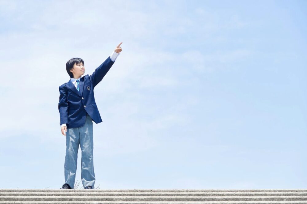 空に向かって手を力強く上げている中学生